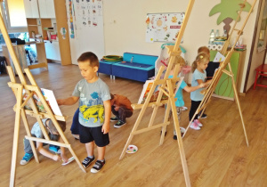 Dzieci malują kropki farbami przy sztalugach