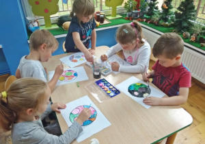 Dzieci malują farbami kolorowankę z piłką