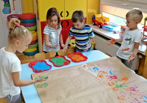 Dzieci malują dłonie farbą i odbijają je na papierze