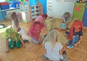 Dzieci siedzą z chustami na głowie - uczestniczą w zabawie