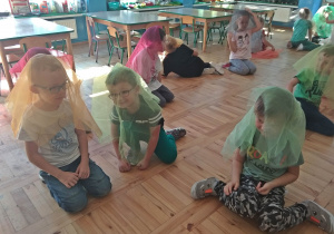 Dzieci siedzą z chustami na głowie - uczestniczą w zabawie