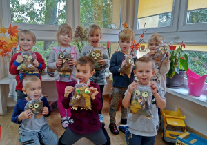 Dzieci prezentują sowy wykonane z folii i liści