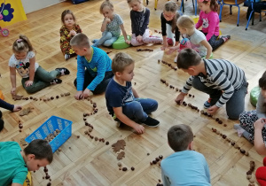 Dzieci układają łańcuchy z kasztanów