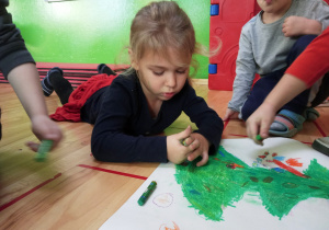 Dziewczynka maluje pastelami choinkę