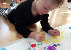 Chłopiec maluje pastelami choinkę