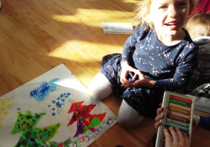 Dziewczynka prezentuje namalowaną choinkę