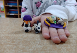 Dziewczynka prezentuje zrobione figurki z plasteliny