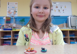 Dziewczynka prezentuje zrobione figurki z plasteliny