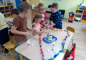 Dzieci sklejają papierowy łańcuch na choinkę