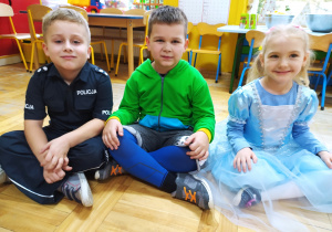 Dzieci siedzą na podłodze prezentują swoje przebrania