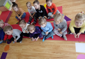 Dzieci siedzą przed tablicą multimedialną