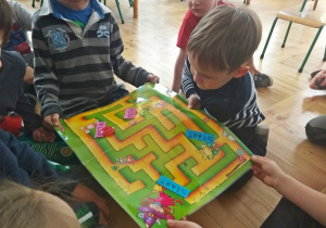 Dzieci przesuwają magnetyczne pionki po tablicy