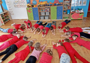 Dzieci leżą na podłodze tworząc serce