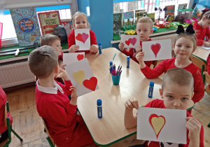 Dzieci pokazują przyklejone papierowe serca