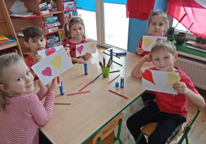 Dzieci pokazują przyklejone papierowe serca