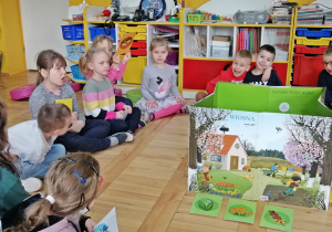 Dzieci siedzą wokół ilustracji przedstawiających pory roku