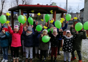 Dzieci unoszą w górę balony i kwiaty z bibuły z okrzykiem przyszła wiosna