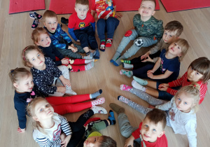 Grupa dzieci 3-letnich siedzi w kole pokazując kolorowe skarpetki na nogach
