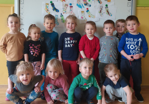 Przedszkolaki z grupy 3-latków stoją przy tablicy z pracami plastycznymi