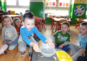 Chłopiec umieszcza plastikowy pojemnik na koszu na plastikowe odpady