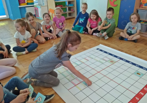 Dziewczyna wybiera kwadracik z ukrytą literą i zagadką