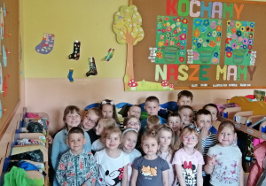Dzieci pozują do zdjęcia pod napisem Kochamy nasze mamy