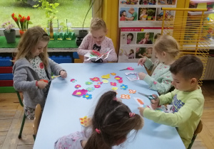 Dzieci sprawnie posługują się nożyczkami podczas wycinania kwiatów
