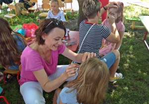 Panie malują dziewczyną rysunki na twarzach