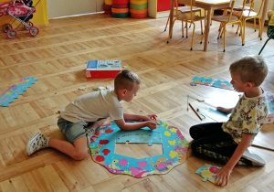 Chopcy układają z części matę do zabawy w łowienie ryb