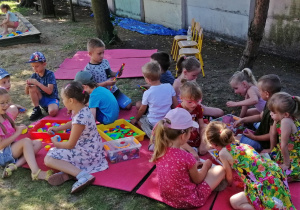 Dzieci bawią się w piasku i klockami na matach