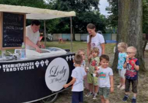 Dzieci jedzą lody w ogrodzie przedszkolnym