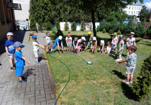 Dzieci przy fontannie wodnej w ogrodzie