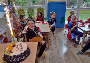 Dzieci oglądają palącą się świeczkę na torcie