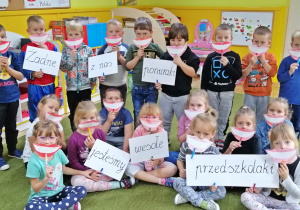 Dzieci pozują do zdjęcia z napisem Żadne z nas ponuraki, jesteśmy wesołe przedszolaki