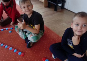 Chłopcy siedzą na dywanie