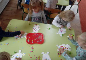 Dzieci przyklejają kolorowe kropki do sylwety Stworka-potworka