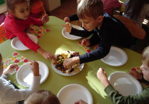 Dzieci wykonują szaszłyki z owoców