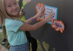 Dziewczyna nakleja obrazki na makietę drzewa