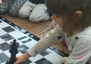 Dziewczynka trzyma figurę króla na szachownicy