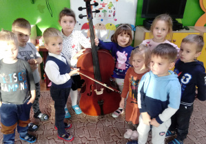Dzieci pozują trzymając wiolonczelę