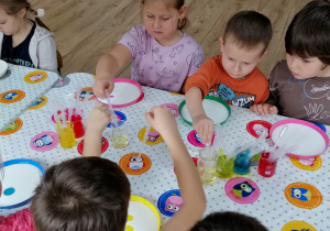Dzieci obserwują zachowanie oleju w połączeniu z mlekiem