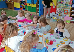 Dzieci tworzą z kolorowych barwników tęczę