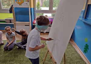 Chłopiec próbuje z zawiązanymi oczami narysować słońce