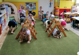 Dzieci na czworakach przechodzą pod trapezem