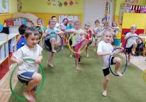 Dzieci unoszą na przemian nogi za pomocą obręczy