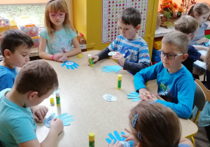 Dzieci naklejają symbol UNICEF-u na szablon dłoni
