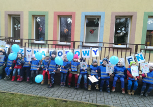 Dzieci pozują przed przedszkolem z niebieskimi balonikami