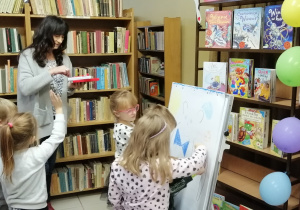 Dzieci po kolei dorysowują elemety postaci misia
