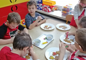 Dzieci ozdabiają pierniczki kolorowym lukrem