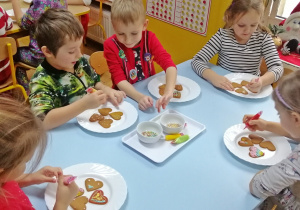 Dzieci rysują na pierniczkach lukrowe wzorki